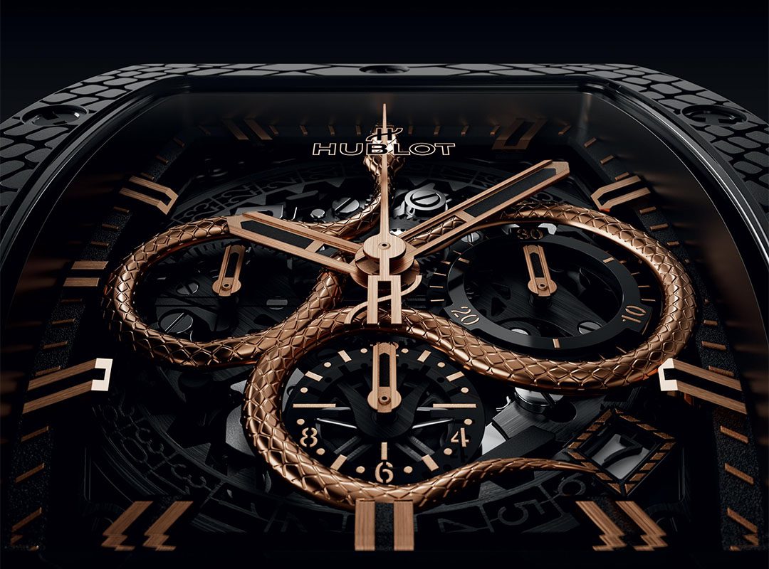 Close-up of a luxury Hublot watch, celebrating the Spirit of Big Bang with a gold serpent design intricately intertwined with the watch hands and dials, set against a dark, elaborate background.