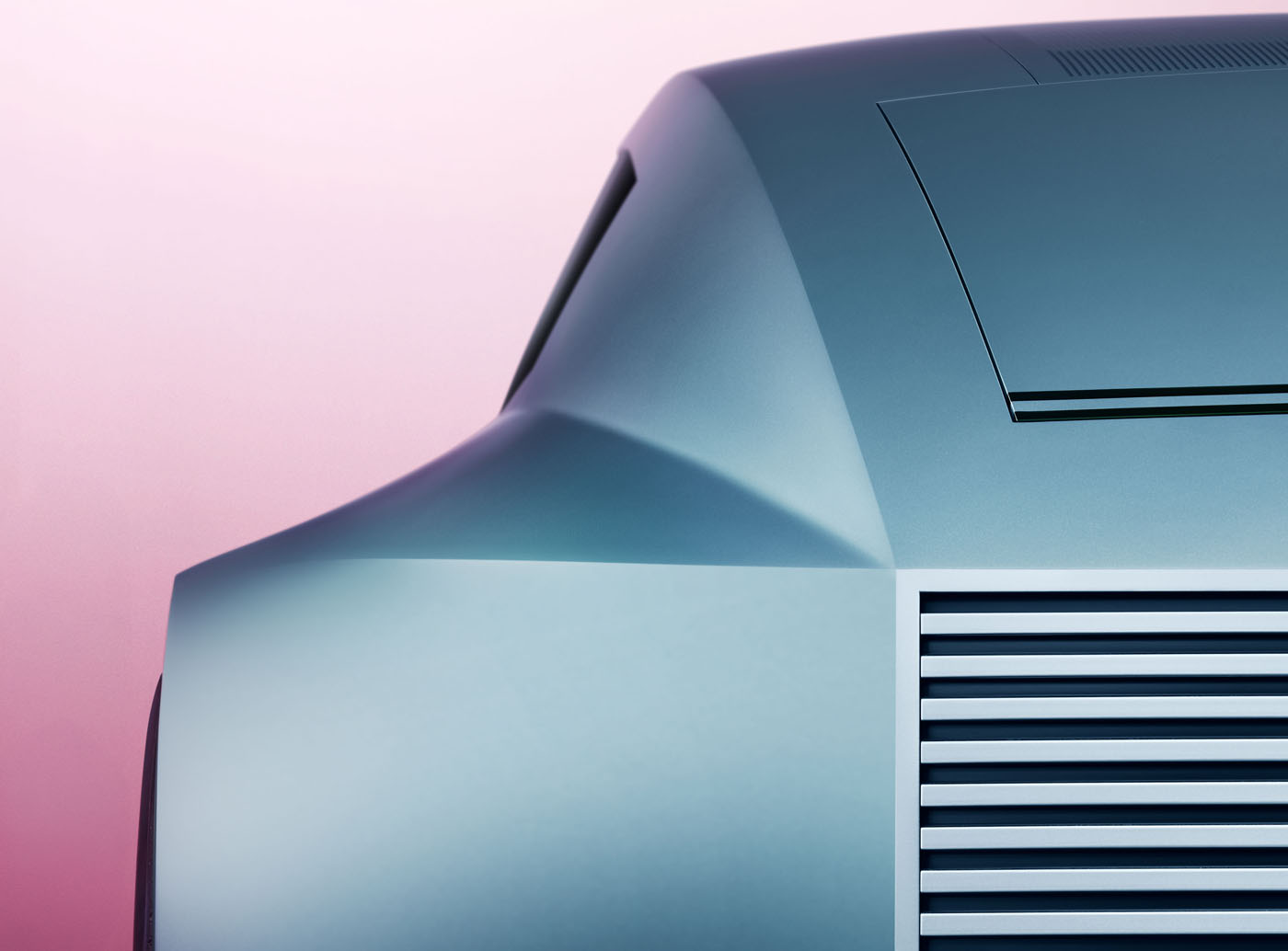 Close-up of a Jaguar Vision Design Concept showing off its futuristic car with smooth, angular design and horizontal vents against a pink gradient background—a striking teaser image for what's to come.