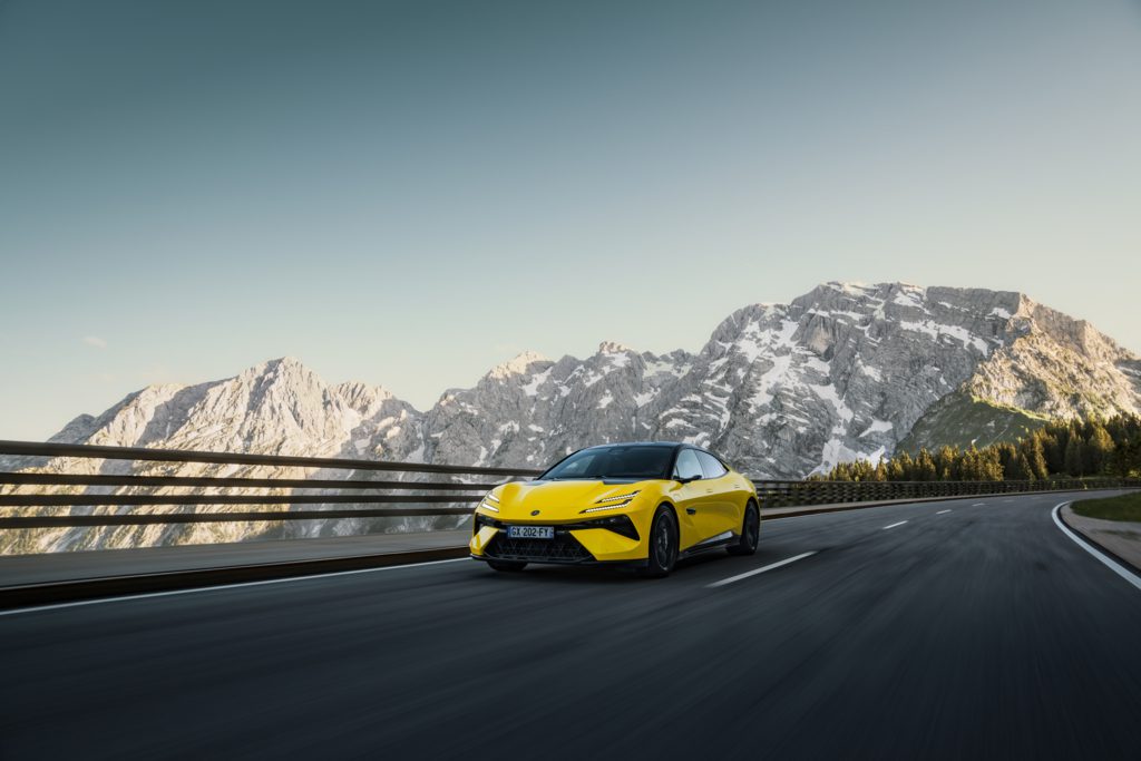 A yellow sports car zips along a mountain highway, with snow-capped peaks framed against a clear sky—a scene that feels as exhilarating as an auto draft on an open road.