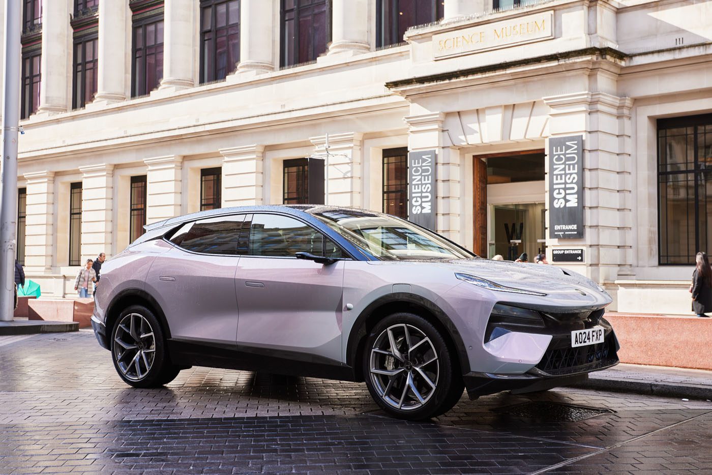 A sleek Eletre Hyper SUV, reminiscent of Lotus design, is parked outside a building adorned with "Science Museum" signs.