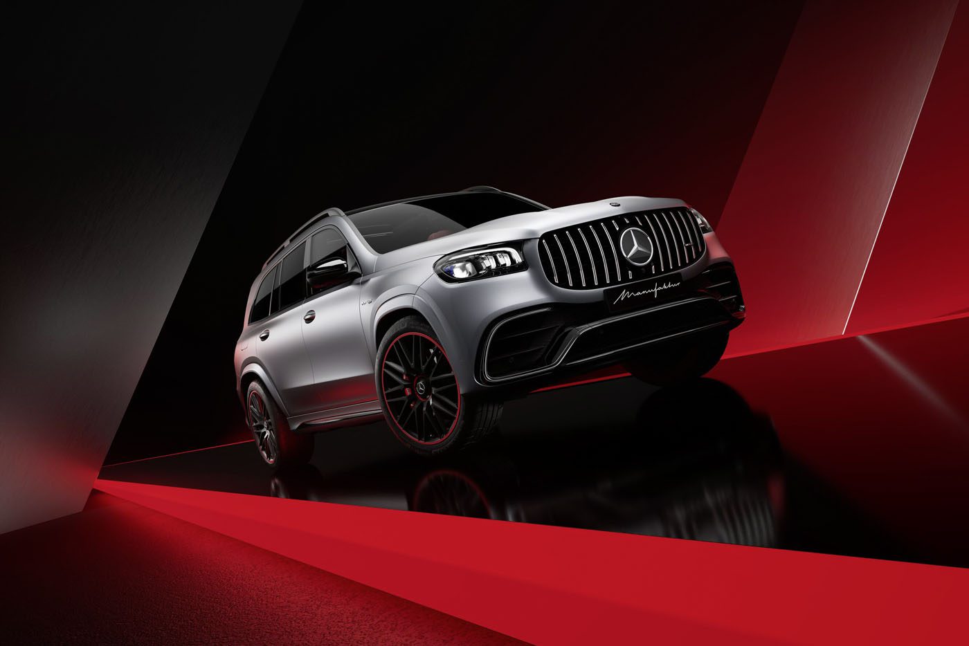 A limited edition Mercedes-AMG GLS 63 in Arctic Silver Edition with sleek black rims is showcased on a glossy black and red geometric background.