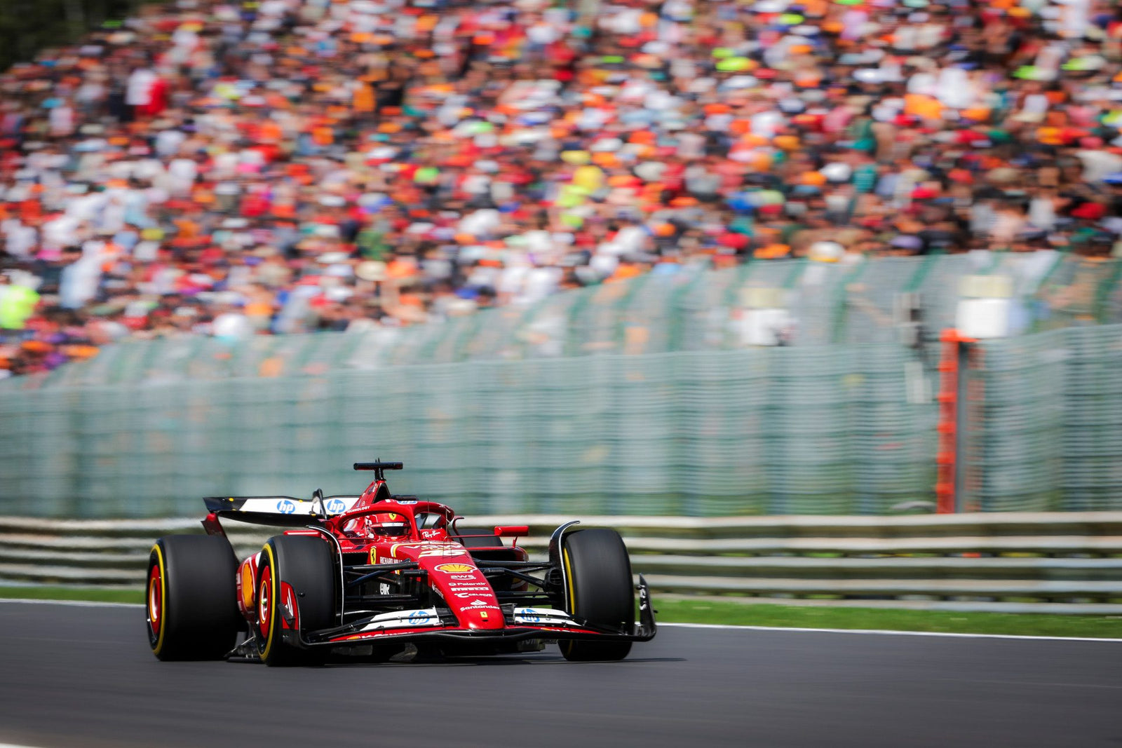 A red Formula 1 car surges from the starting grid, speeding along the track against the backdrop of a blurred crowd, embodying the thrill of the 2025 F1 Season.