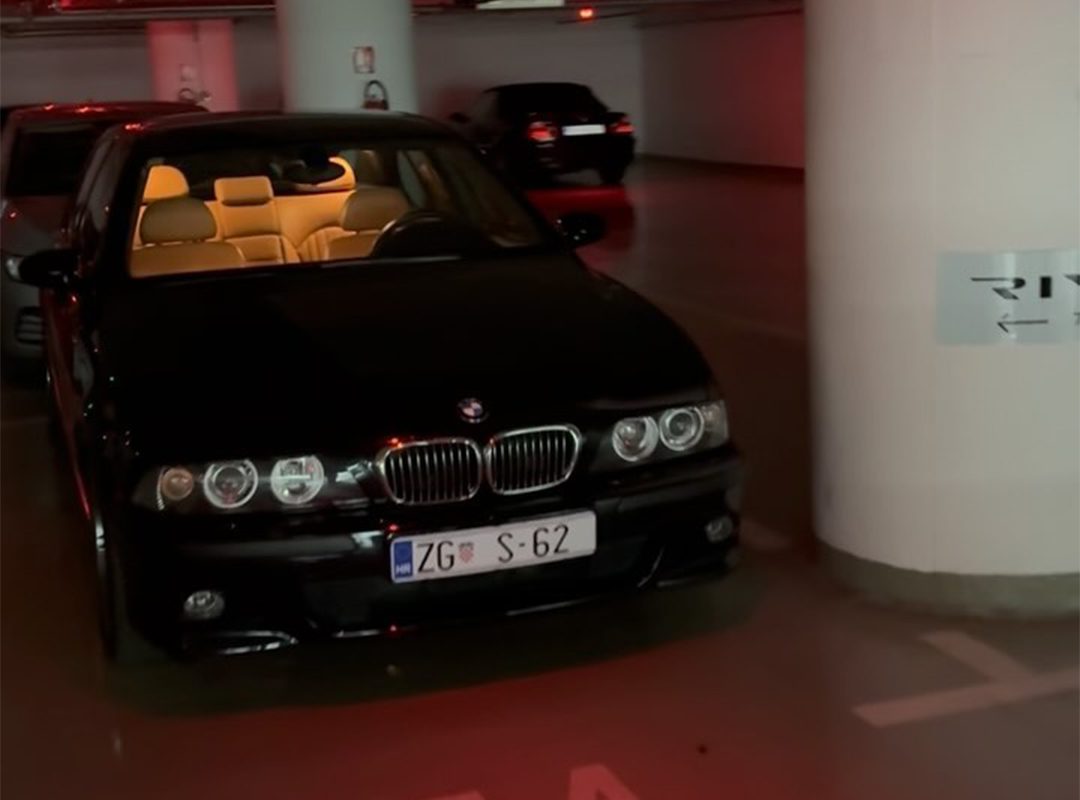 A sleek black BMW M5 is parked in a dimly lit parking garage, its interior beautifully illuminated like the cockpit of a hypercar.