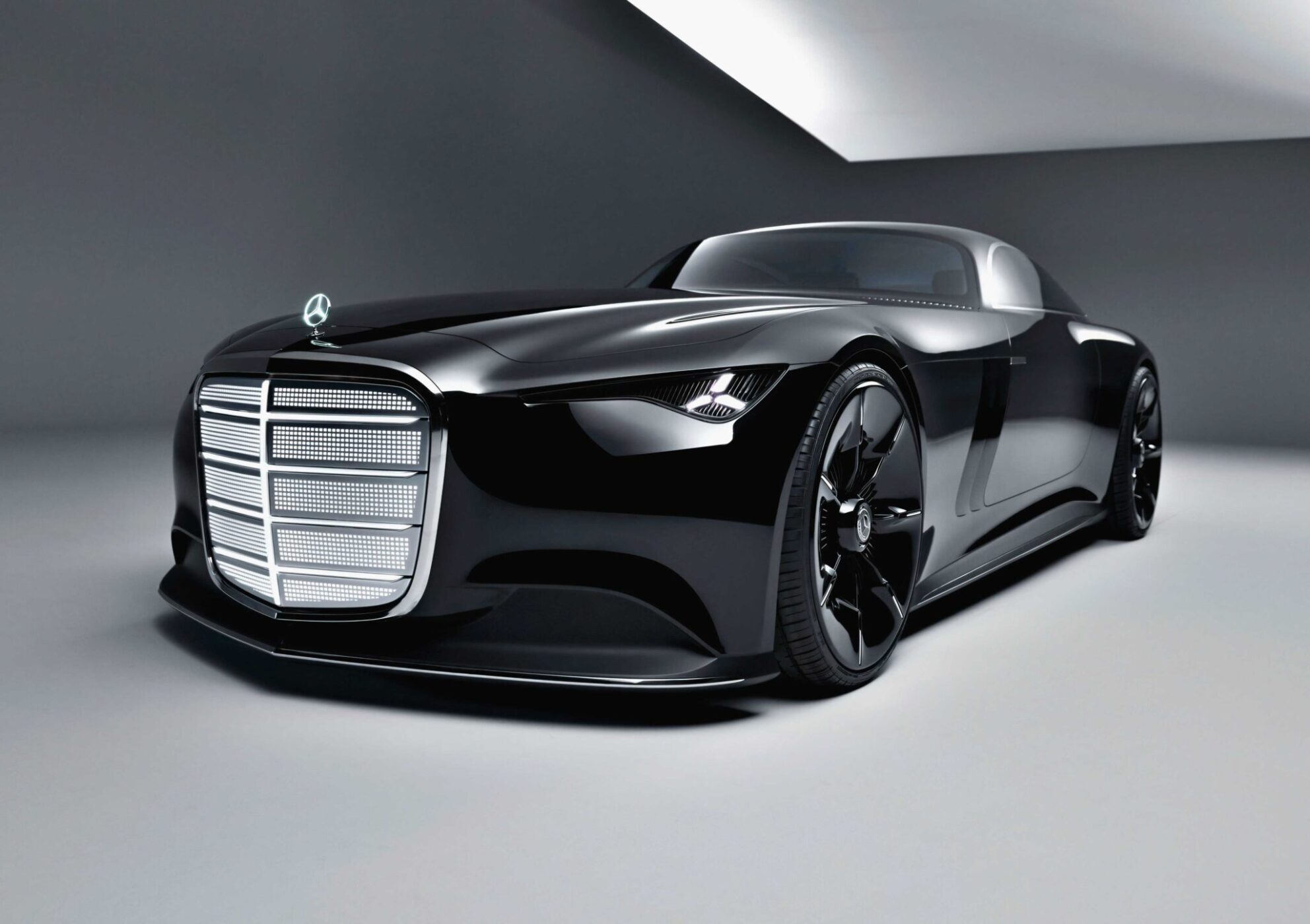 A sleek, black Mercedes-Benz luxury concept car with a prominent grille and low profile, the Vision Iconic is displayed in a modern, minimalistic showroom, embodying the elegance of the Electric Era.