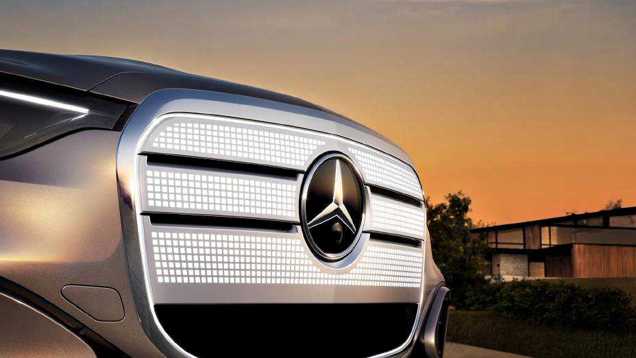 Close-up of the Bold New Face: Electric GLC ushers in a new era of Mercedes-Benz design, featuring an illuminated LED grille pattern at sunset with a modern house in the background.