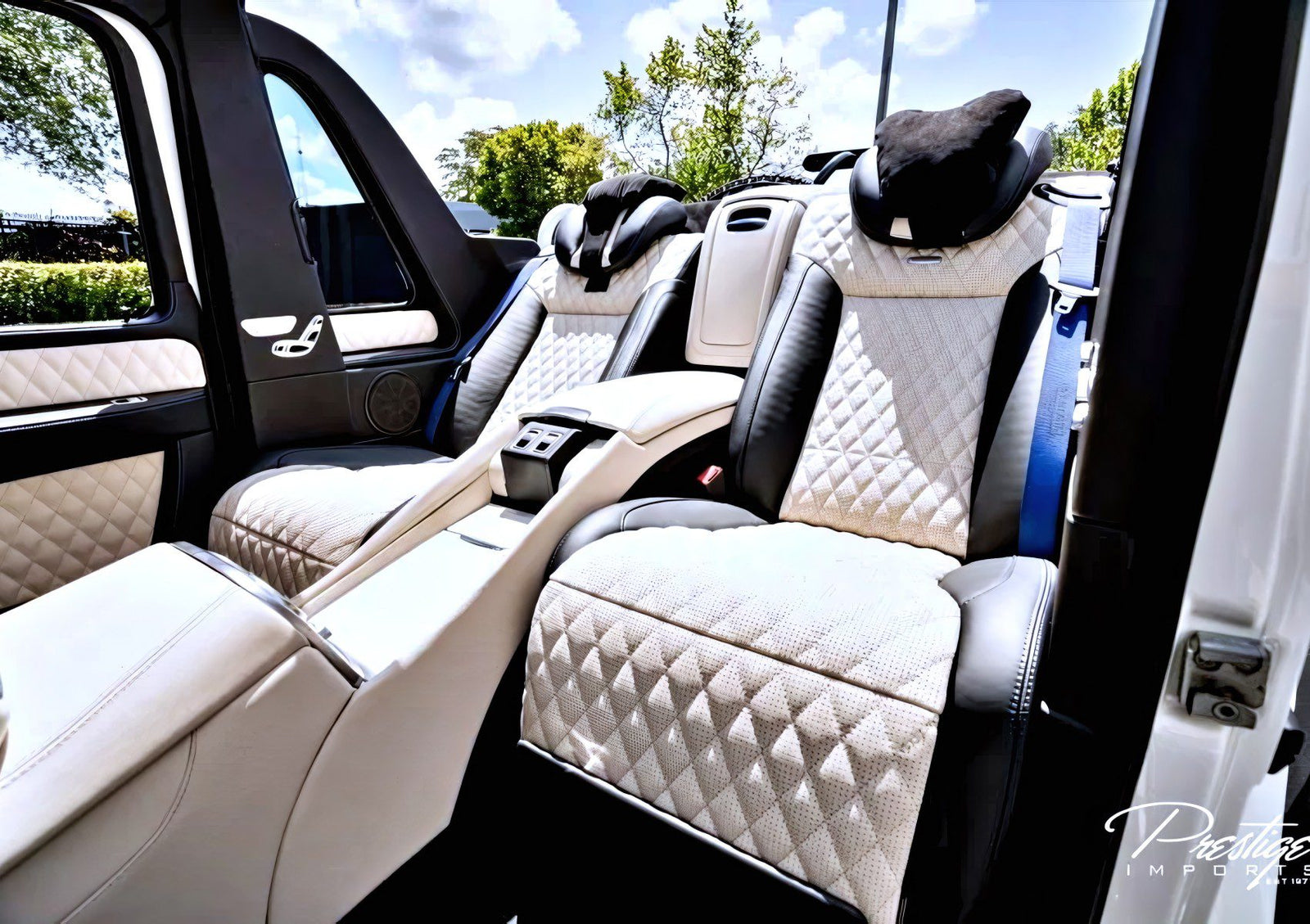 Interior of a luxury Mercedes-Maybach G650 for sale, featuring two large quilted leather seats with headrests and a central armrest console under bright daylight.