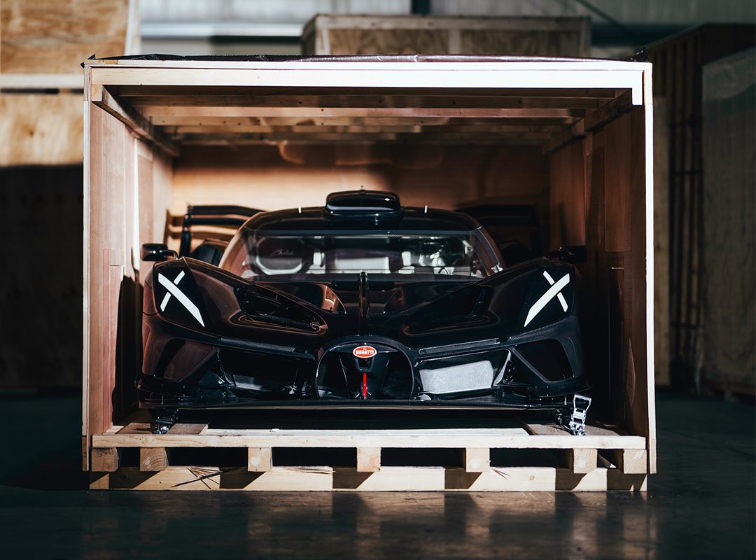 Tucked securely within the wooden crate, a sleek black Bolide Hypercar from Bugatti peeks out, hinting at its breathtaking design and power.