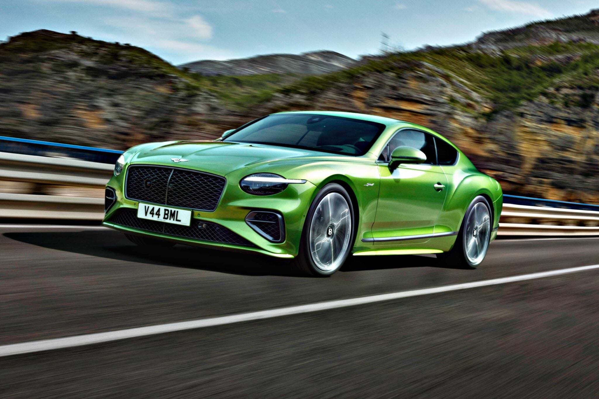 A green Bentley coupe drives on a highway with mountains and trees in the background—Review: 2026 Bentley Continental GT Speed.