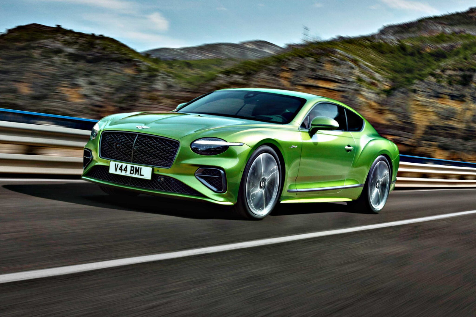 A green Bentley coupe drives on a highway with mountains and trees in the background—Review: 2026 Bentley Continental GT Speed.