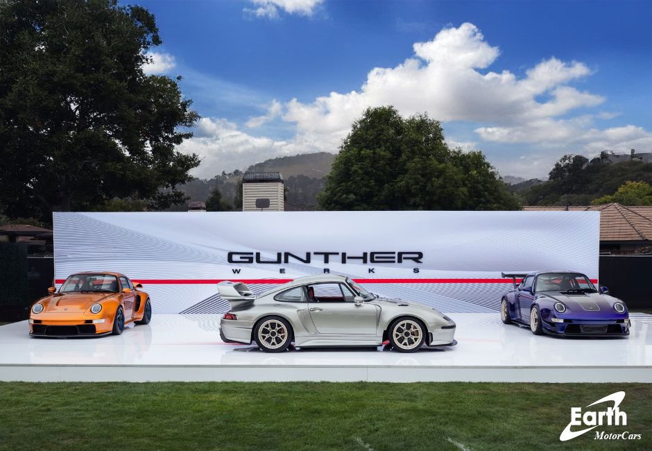 Three sports cars are displayed outdoors on a white platform in front of a "Gunther Werks" backdrop under partly cloudy skies, highlighting the latest from Gunther Werks dealers in the U.S. and Earth MotorCars.