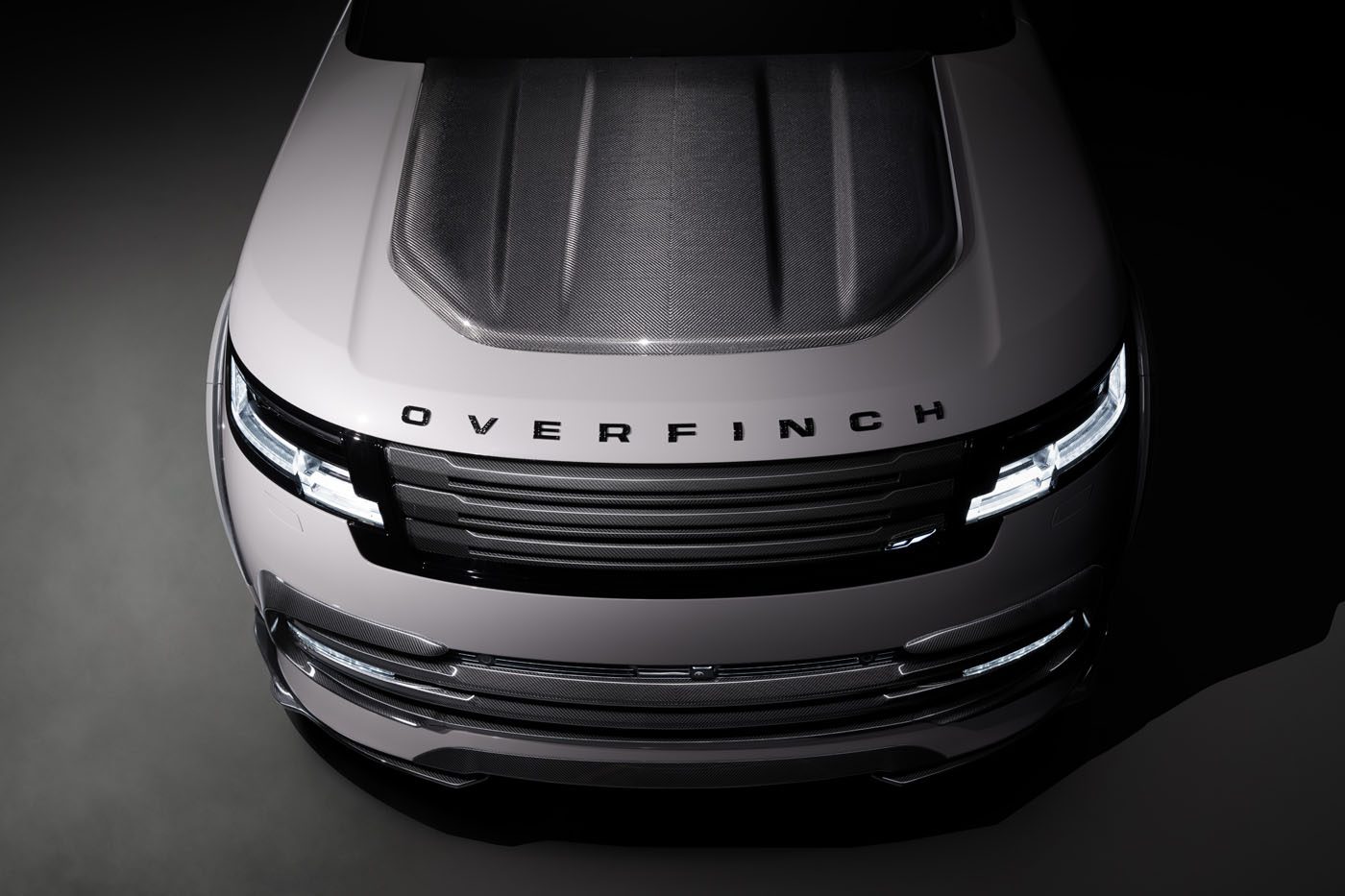 Top view of a silver vehicle with a carbon fiber hood, showcasing the "Overfinch" branding on the front. The design embodies a powerful aesthetic, characteristic of the Velocity Edition.
