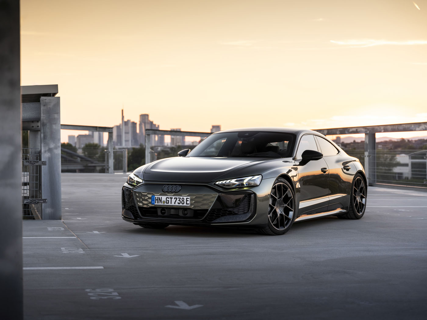 The sleek black Audi RS e-tron GT, known for its quickest accelerating performance, is parked in a rooftop lot at sunset.