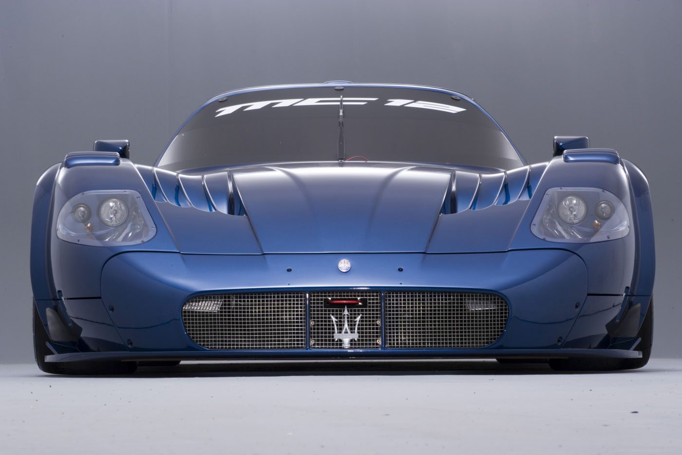 Front view of a blue Maserati sports car with "MC12" displayed on the windshield, embodying the elegance typically celebrated at Auto e Moto d'Epoca.