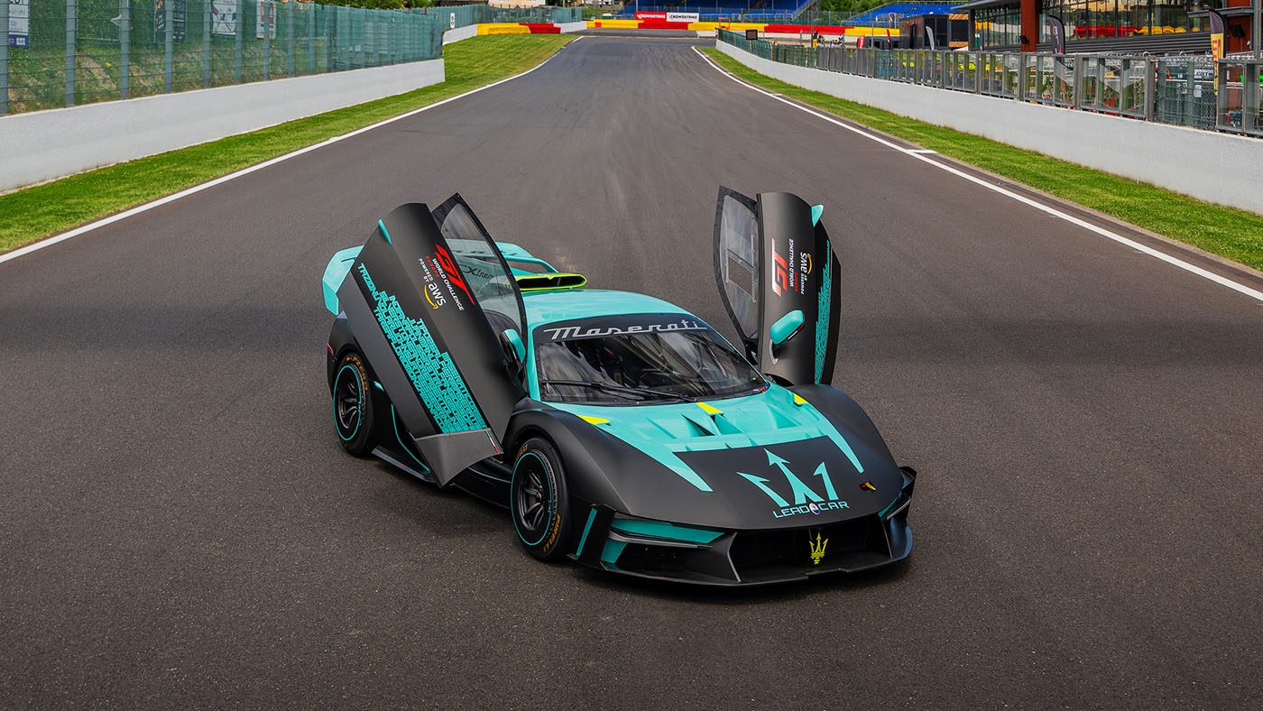 A teal and black Maserati MCXtrema with its butterfly doors open, sporting a Historic Livery, is parked on a race track.