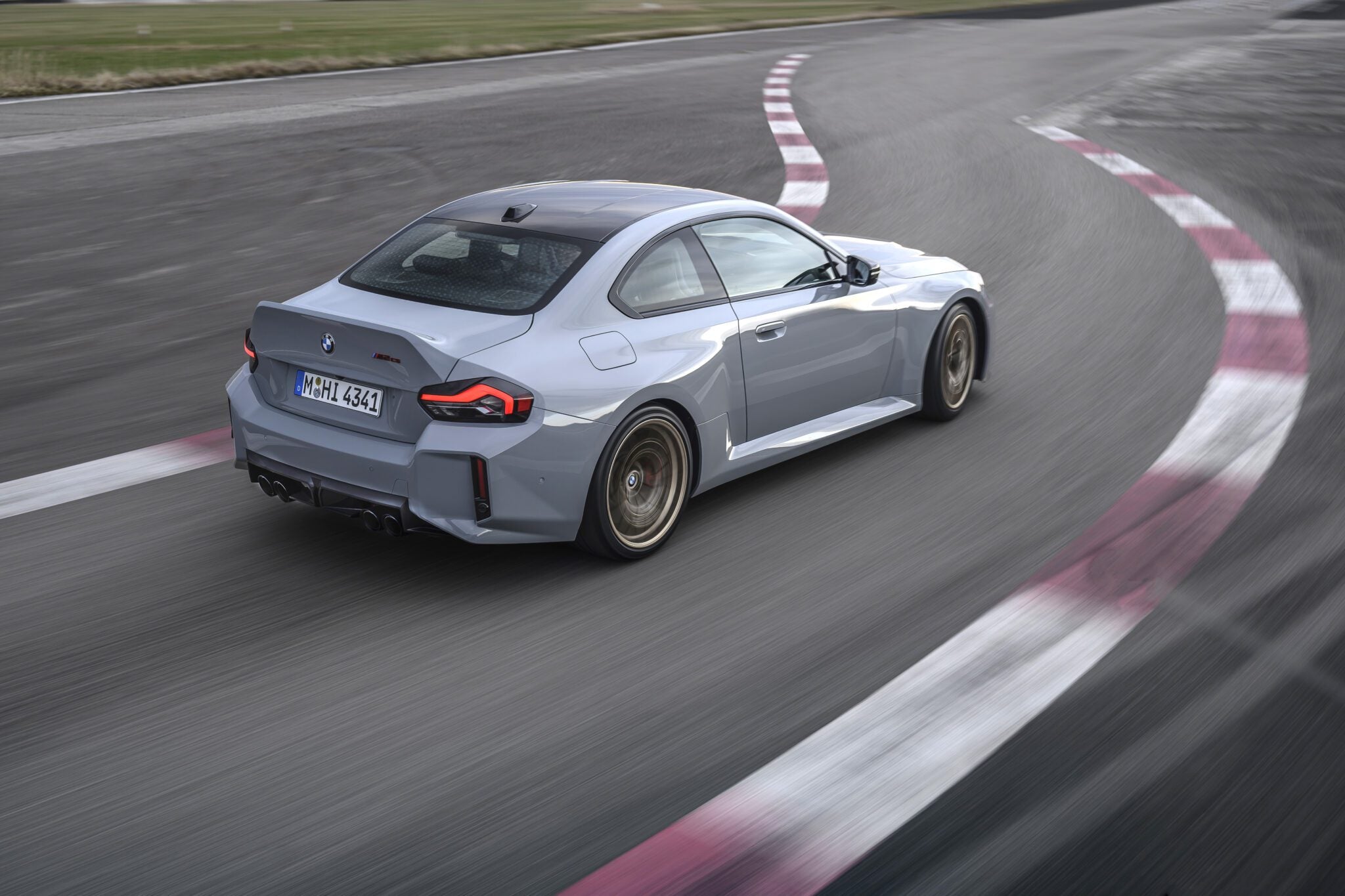 A grey BMW coupe from BMW USA drives on a racetrack, captured from behind as it rounds a corner—exemplifying the dynamic spirit fueling BMW’s sales growth in H1 2025.