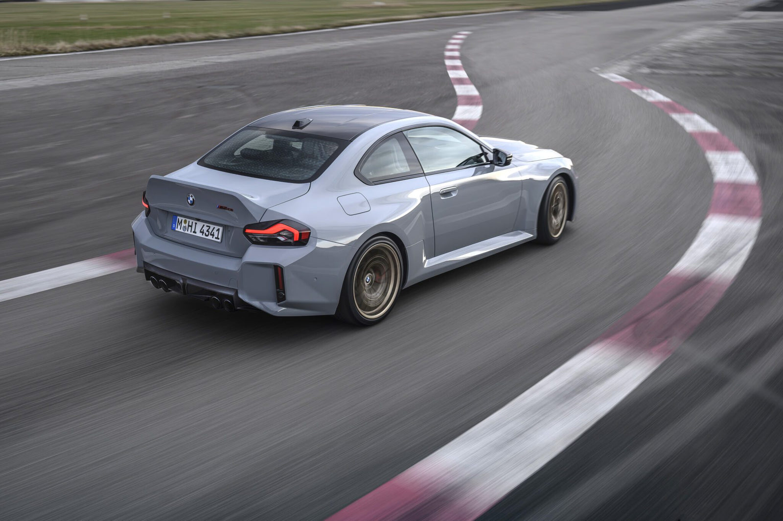 A grey BMW coupe from BMW USA drives on a racetrack, captured from behind as it rounds a corner—exemplifying the dynamic spirit fueling BMW’s sales growth in H1 2025.