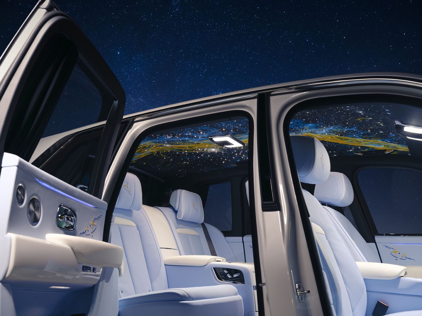 The interior of a Rolls-Royce Cullinan features white leather seats, open doors, and a hand-painted starlight headliner on the ceiling, all set against a night sky backdrop.