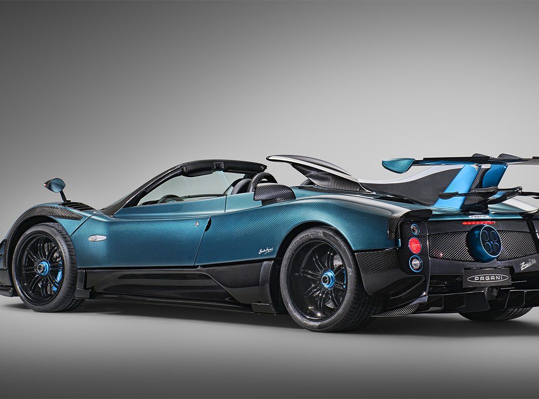 A blue and black Blue Carbon Zonda Roadster is shown angled from the rear, highlighting its aerodynamic design and carbon fiber details—a stunning 1-of-1 Pagani Unico masterpiece.