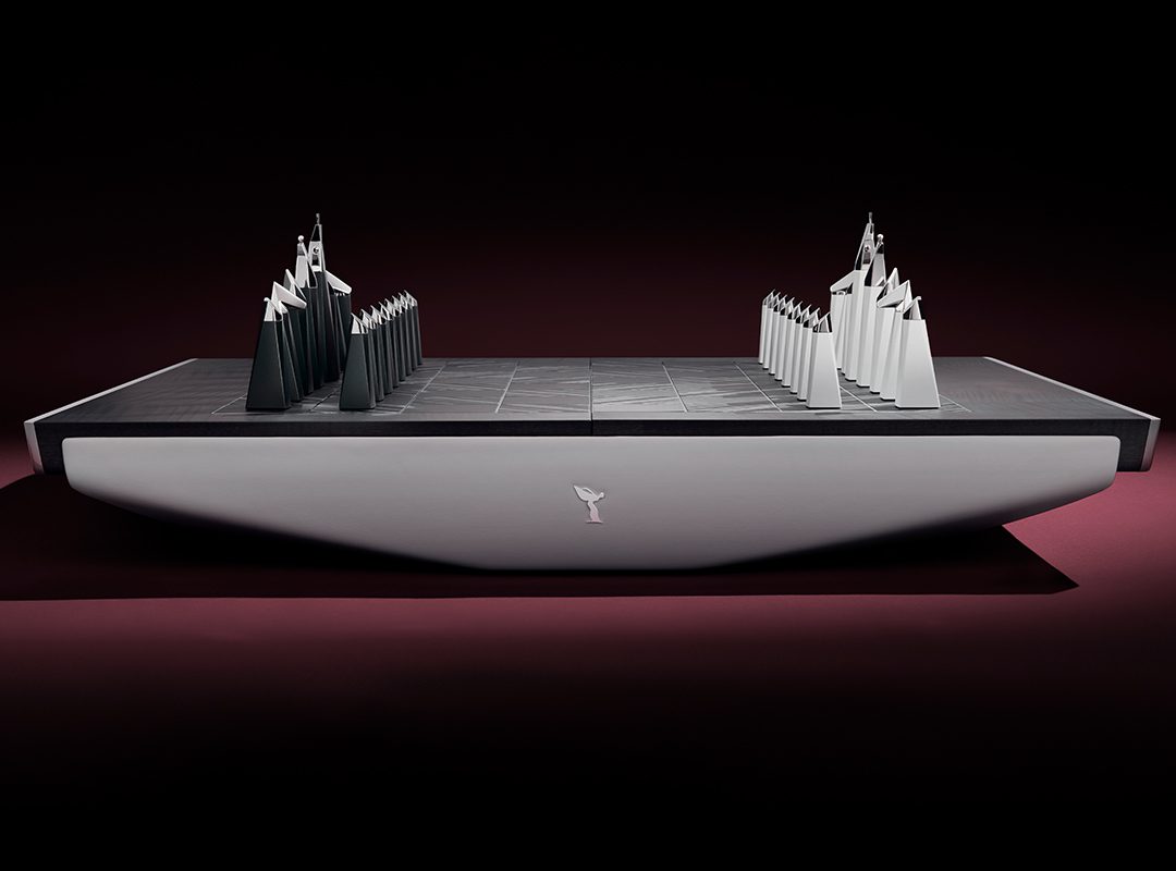 A bespoke chess set featuring abstract, angular black and white pieces on a minimalist rectangular board, viewed from the side against a dark background—an ultra-luxury design reminiscent of Rolls-Royce sophistication.