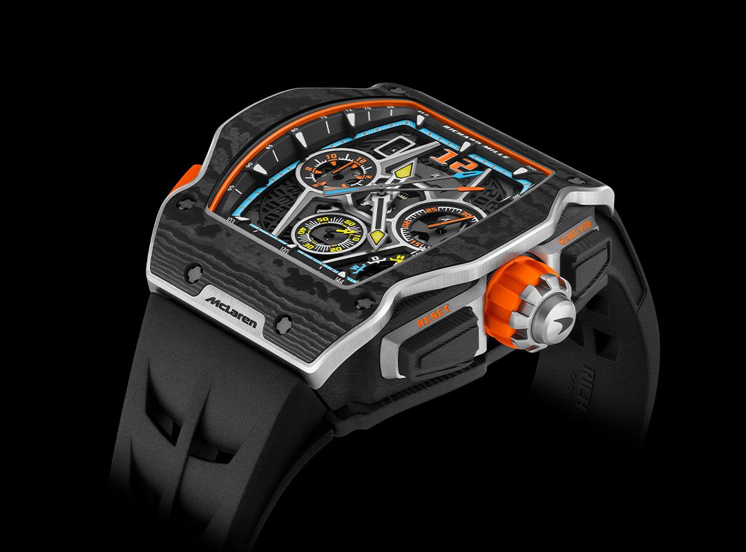 This automotive-inspired watch features a futuristic angular design with orange accents and detailed dials, all on a sleek black strap, making it a standout piece in 2024 watch releases.