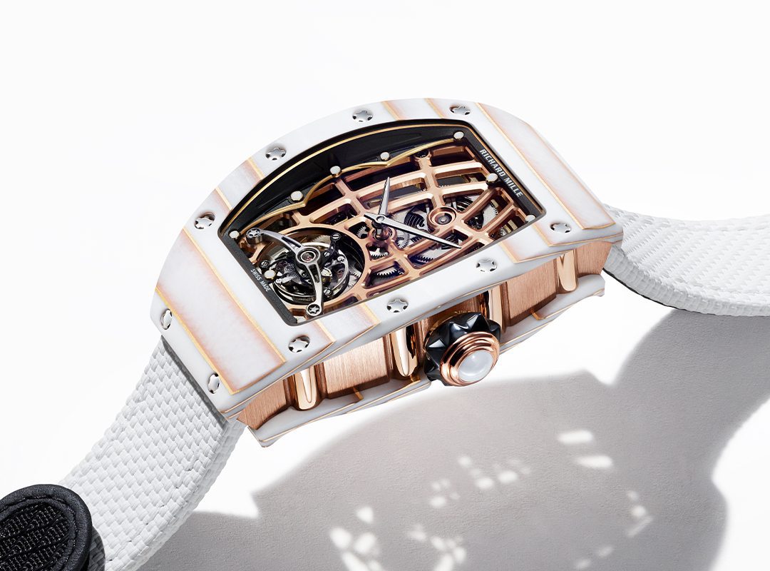 Experience the elegance of the RM 74-02 by Richard Mille, a luxury watch with an Automatic Tourbillon. It features a white strap and an exposed, intricate mechanism within a rectangular gold-tone casing.