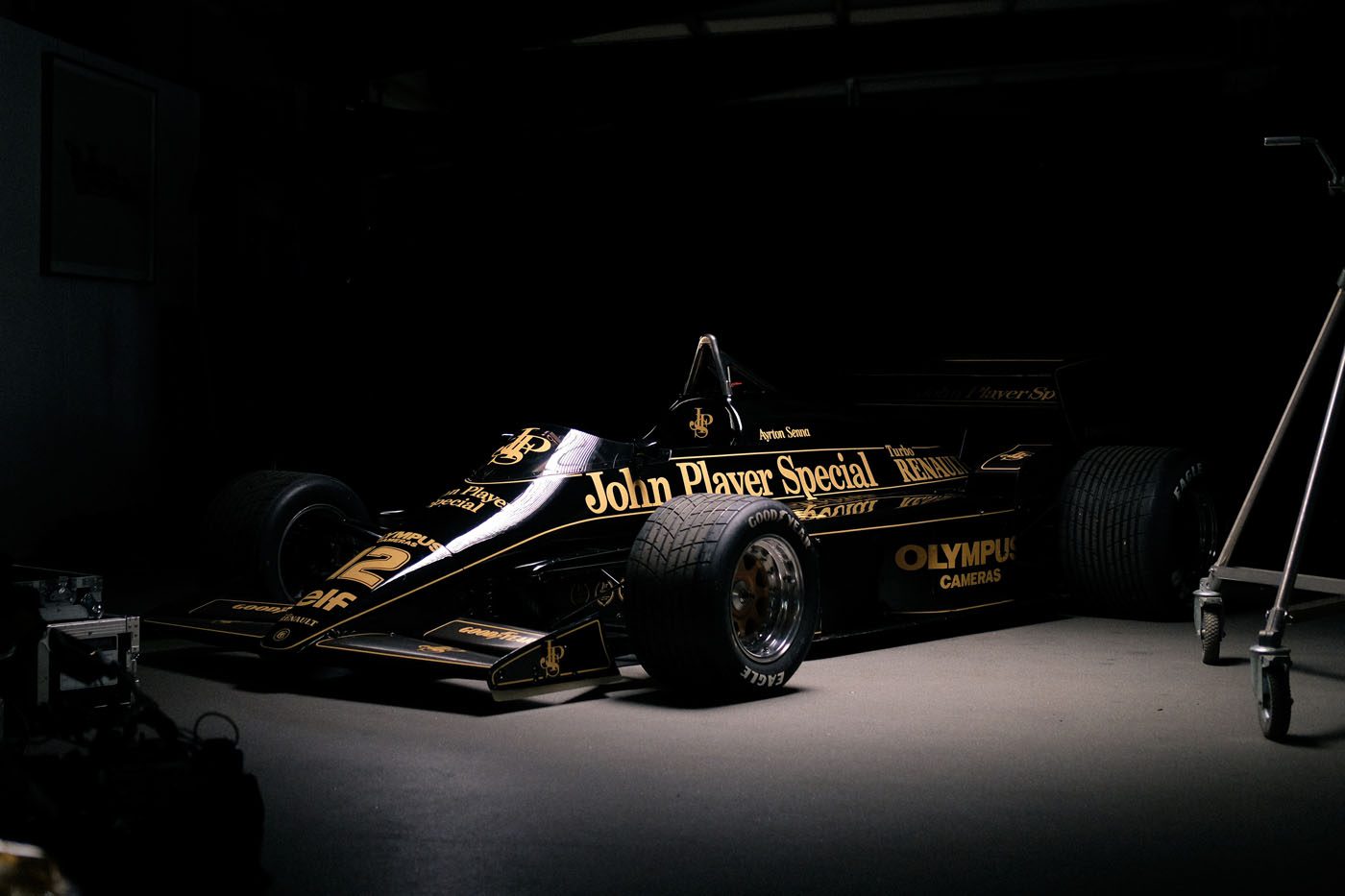 Black and gold Formula 1 car with "John Player Special" on the side, parked in a dimly lit garage.