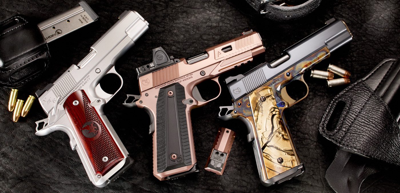 Three Nighthawk Custom handguns with detailed grips are displayed on a dark surface, surrounded by magazines, bullets, and a leather holster.