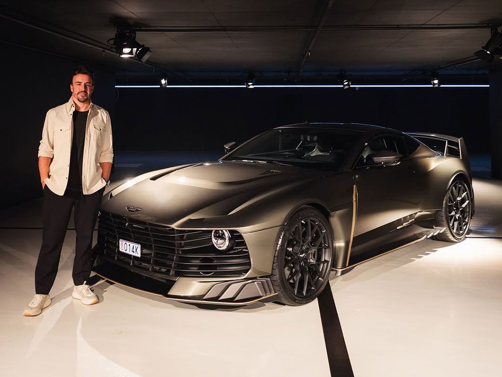 In a dimly lit showroom, a man stands beside a sleek, dark Aston Martin sports car, its unique grille and angular design echoing the elegance of Monaco's streets.