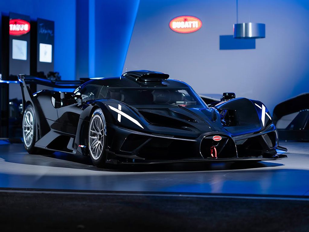 At Miller Motorcars, a sleek black hypercar is showcased indoors under blue lighting, flaunting aerodynamic design features and a prominent rear wing.