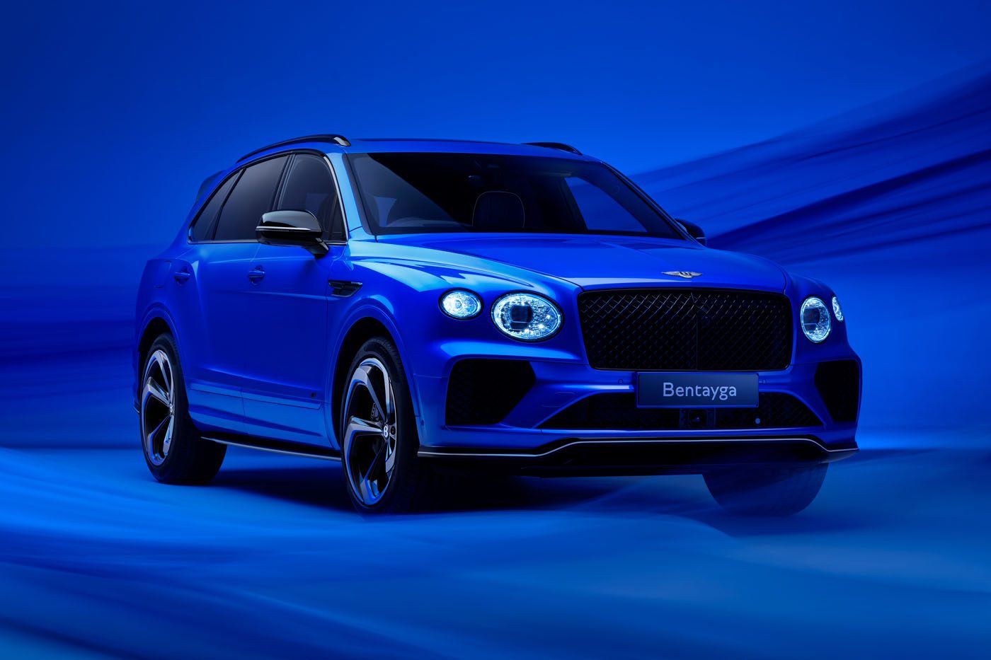 A blue luxury SUV, boasting the sleek design of a Bentayga S, is parked against a matching blue background.