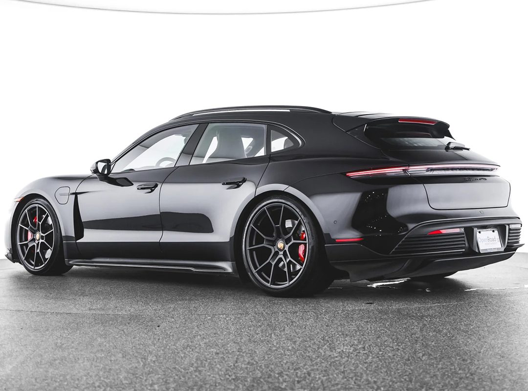 A black Porsche Taycan Cross Turismo wagon, the ultimate EV for sale, is parked indoors and shown from the rear three-quarter view.