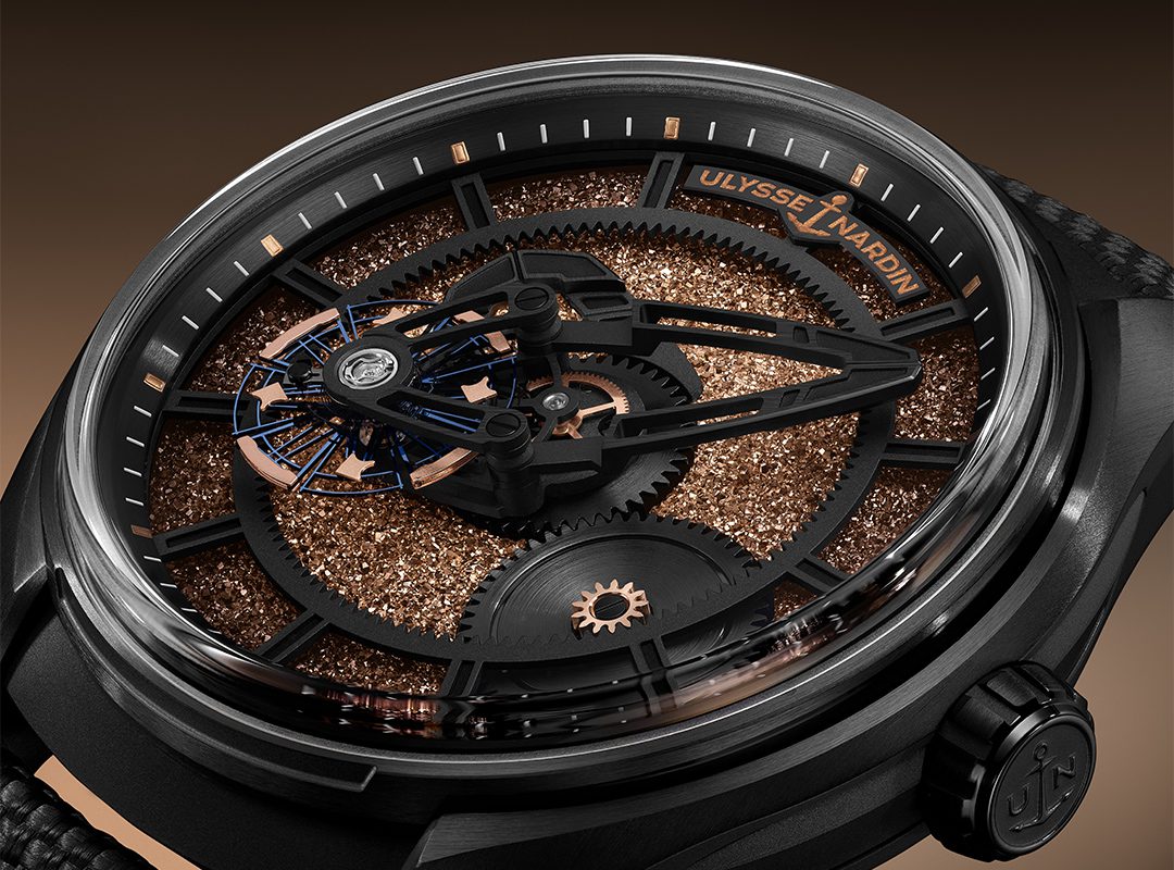 Close-up of a limited edition Ulysse Nardin wristwatch with exposed gears, copper-toned textured dial, and skeletonized hands inside a black case.
