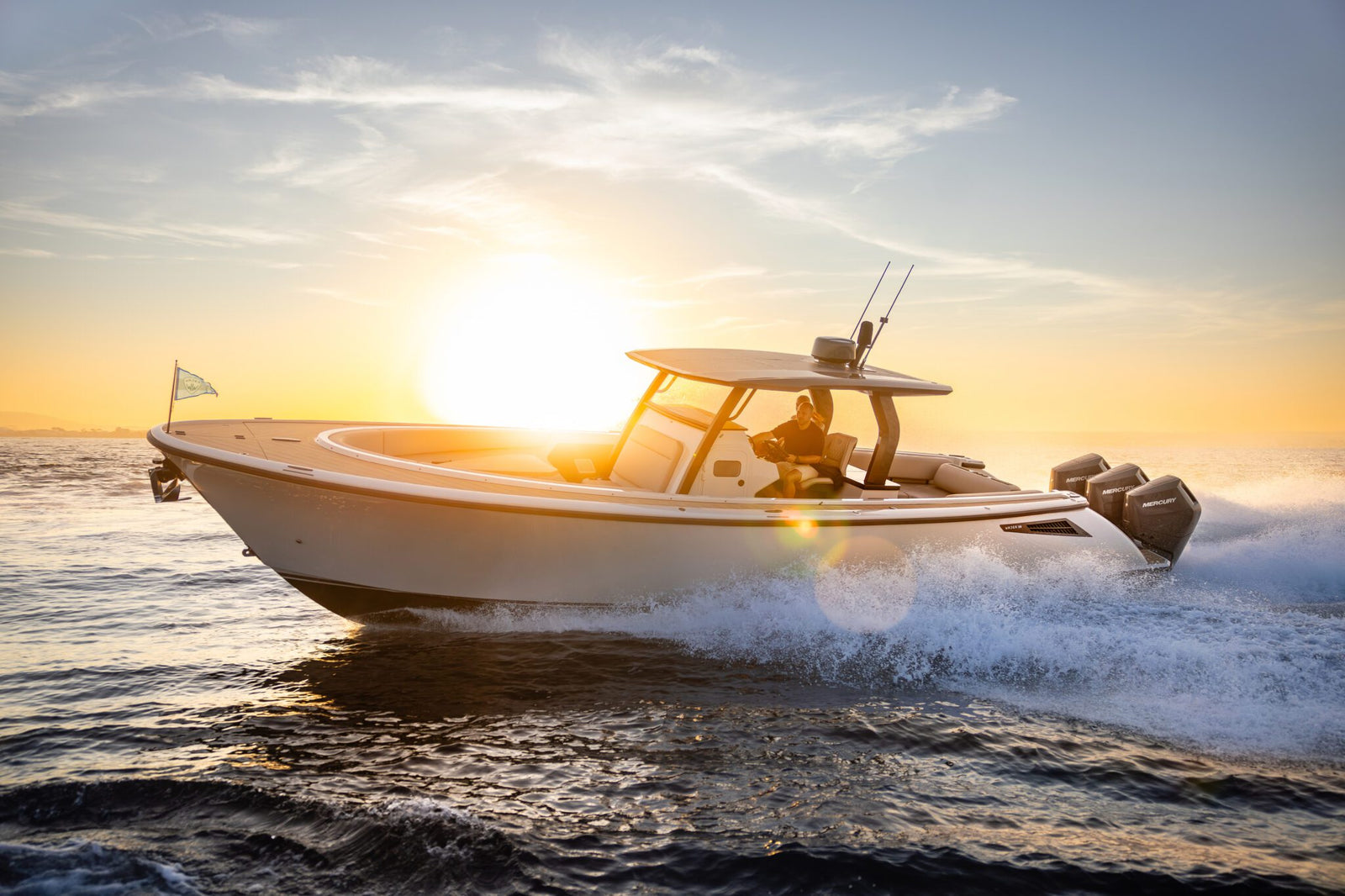 A Wajer Yacht glides swiftly across the water at sunset, with a person at the helm, showcasing the luxury of innovation while creating a trail of waves.