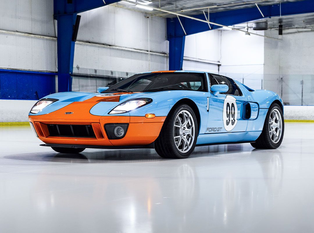 A stunning Ford GT Heritage Edition, boasting a blue and orange paint job with the iconic number 98—an homage to Wayne Gretzky—is parked indoors on a polished surface. Now available for sale, this beauty is ready to turn heads wherever it goes.