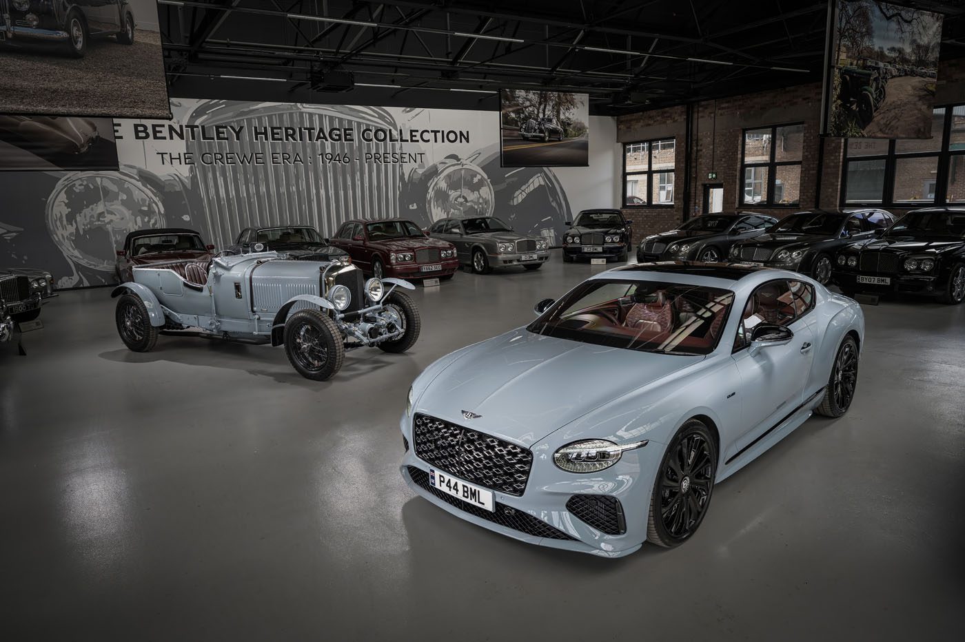 A modern Bentley coupe featuring Heritage Leather as an interior option stands beside a vintage Bentley, both displayed in a showroom with other classic vehicles and Bentley Heritage Collection signage in the background.