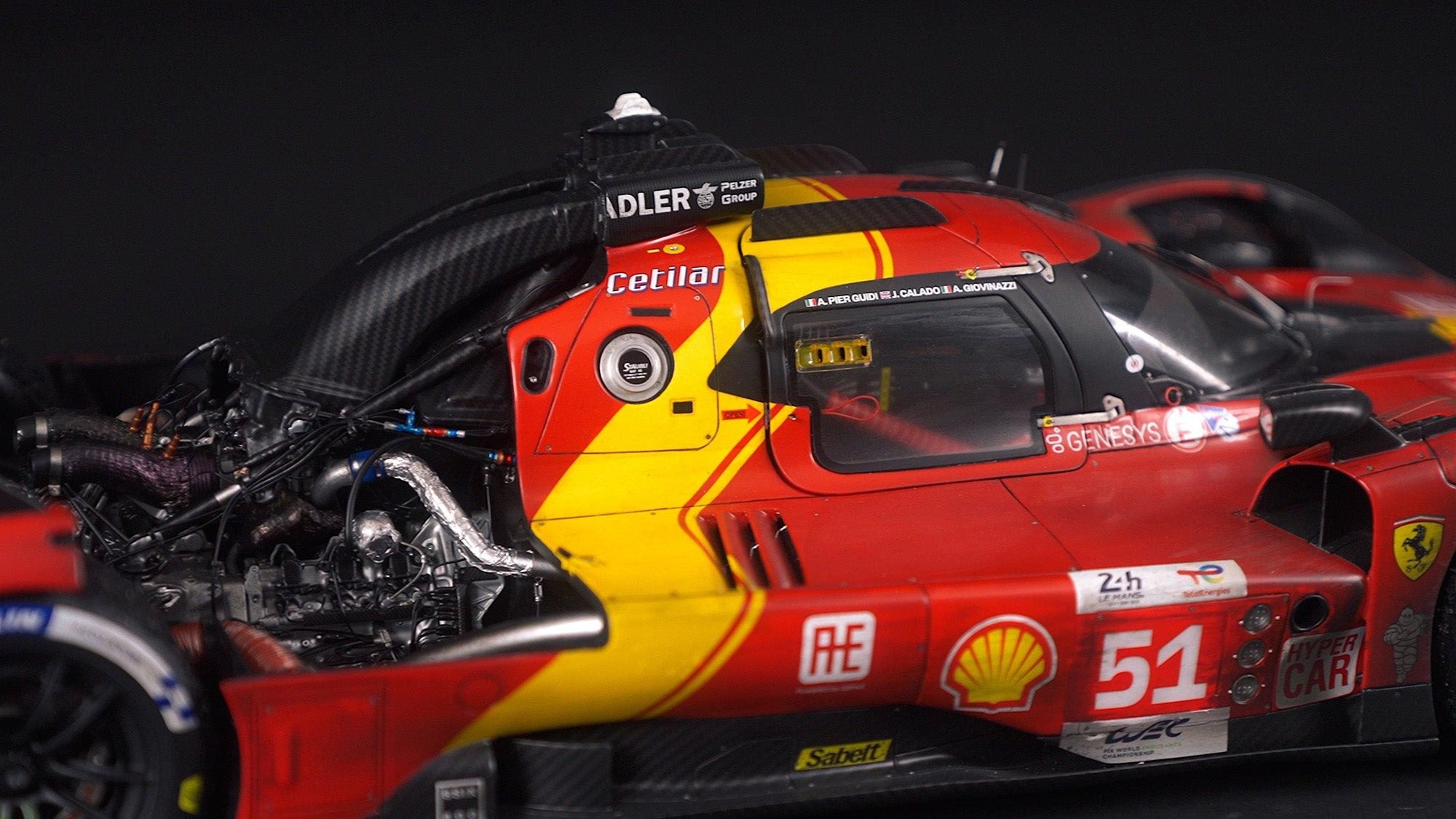 Close-up view of a red and yellow Ferrari race car from the Amalgam Collection, highlighting the cockpit, exposed engine components, and number 51 on the door.