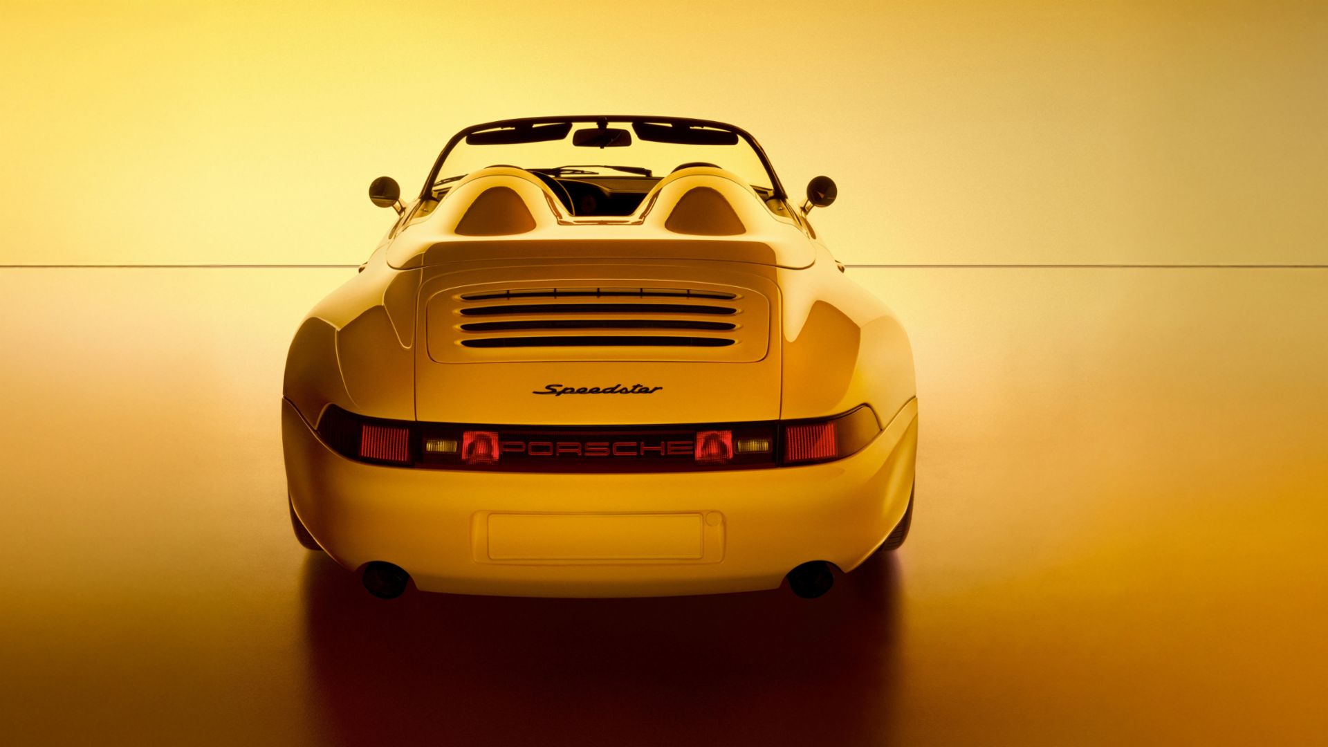 Rear view of a yellow Porsche Speedster convertible, a stunning example of Porsche exclusive craftsmanship, photographed against a warm yellow background.