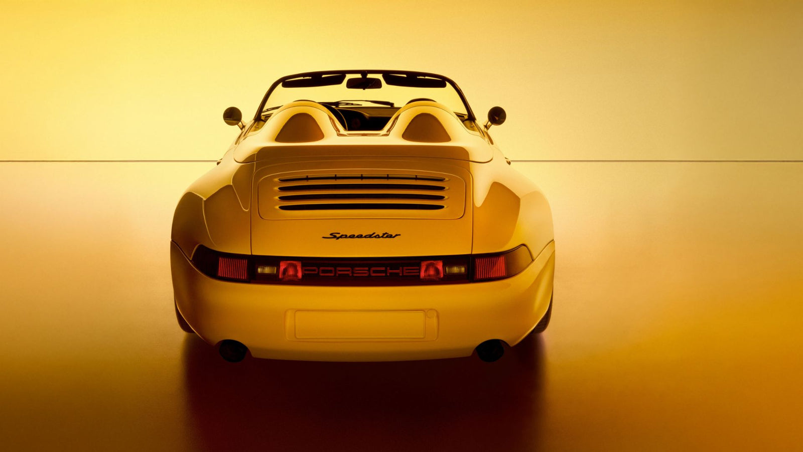 Rear view of a yellow Porsche Speedster convertible, a stunning example of Porsche exclusive craftsmanship, photographed against a warm yellow background.