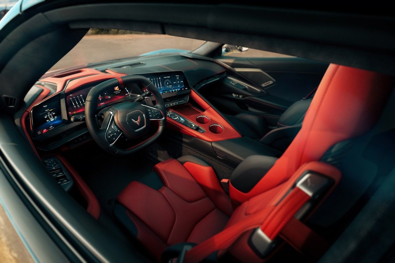 View of a modern 2026 Chevrolet sports car interior featuring red and black leather seats, digital dashboard, and a steering wheel with a Corvette logo.