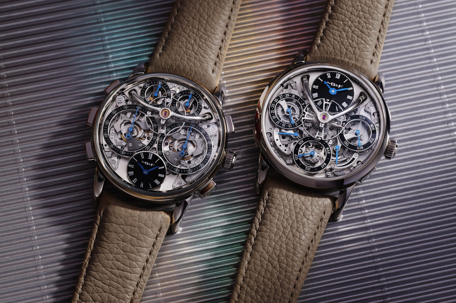 Displayed on a textured surface are two intricate mechanical watches with transparent dials and beige leather straps. One is a limited-edition LM by MB&F, marking their 20th anniversary in exquisite style.