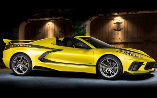 A yellow convertible muscle car with "Yenko SC" on the side, built by Specialty Vehicle Engineering, is parked in front of wooden double doors under outdoor lighting.