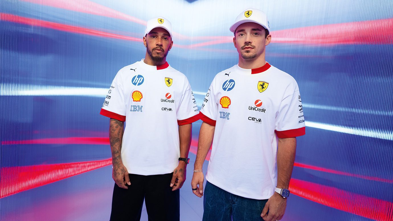 Two men wearing white Scuderia Ferrari team shirts and caps stand side by side against a futuristic, red and blue striped background, showcasing exclusive Miami Limited Edition PUMA apparel.