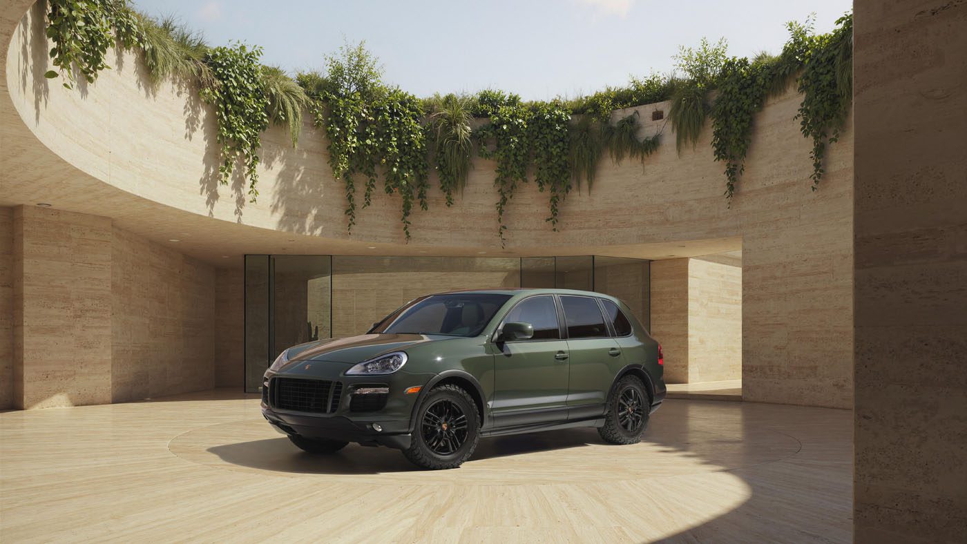 A green Porsche Sonderwunsch SUV is parked in the center of a circular open courtyard with beige stone walls and greenery above.