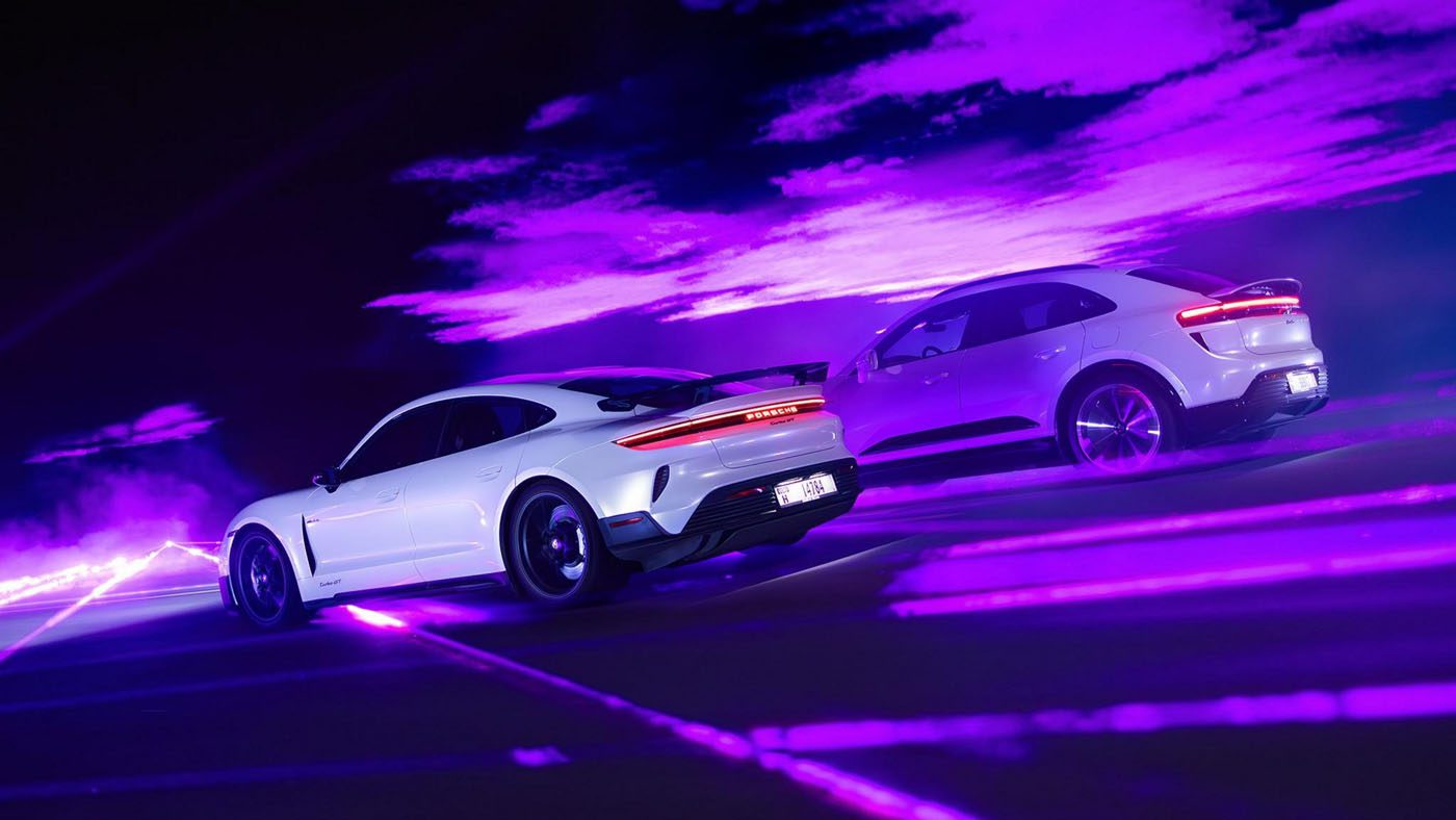 Two white Porsche sports cars race through purple light effects in a dark setting. The scene is dynamic and futuristic, echoing the speed of light with vibrant, illuminated trails.