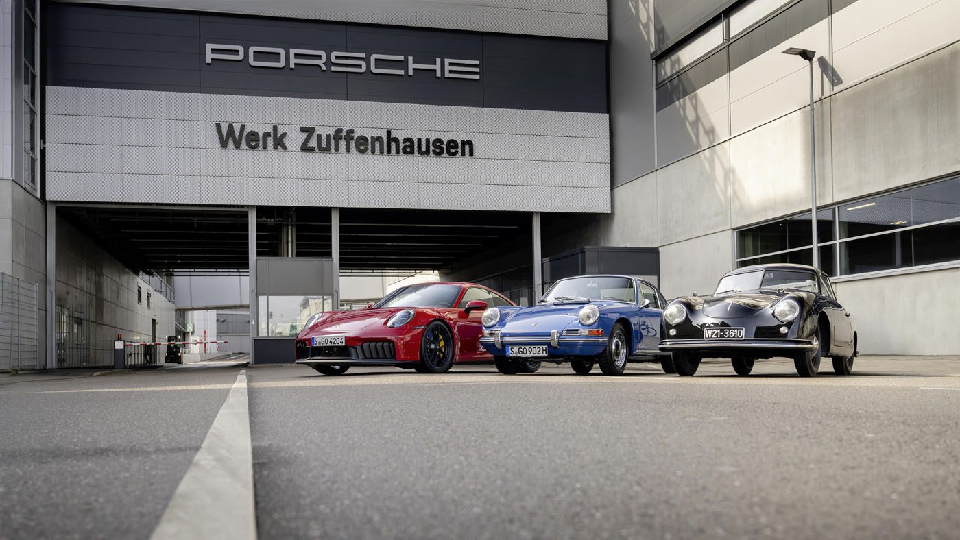 Three Porsche cars, resplendent in red, blue, and black, proudly stand before the historic Zuffenhausen headquarters, marking 75 years of automotive excellence.