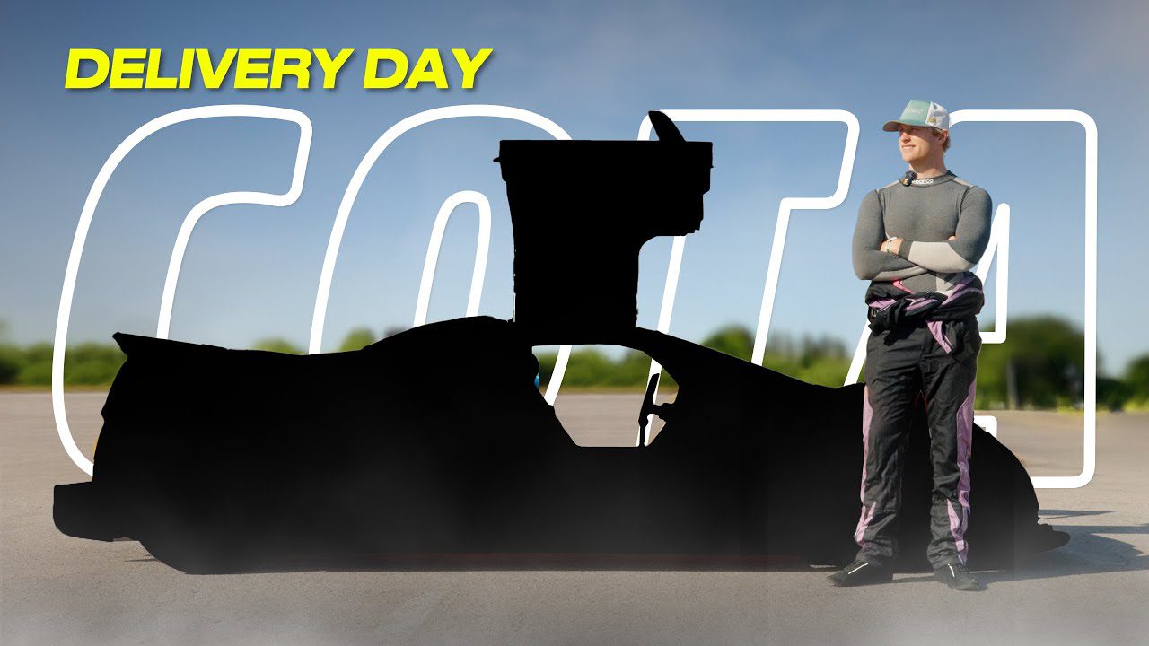 A person in racing gear stands beside a black-silhouetted Gumpert Apollo on a sunny "DELIVERY DAY"—ready to hit COTA as a U.S. street legal supercar.