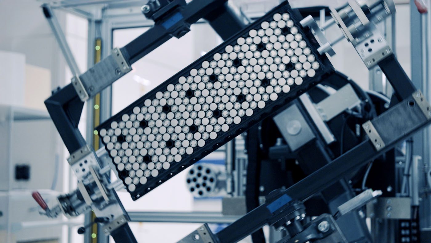 A close-up of machinery holding a rectangular tray filled with cylindrical cells, likely in a laboratory or manufacturing setting—reminiscent of how Rimac Technology has revolutionized advanced battery systems.