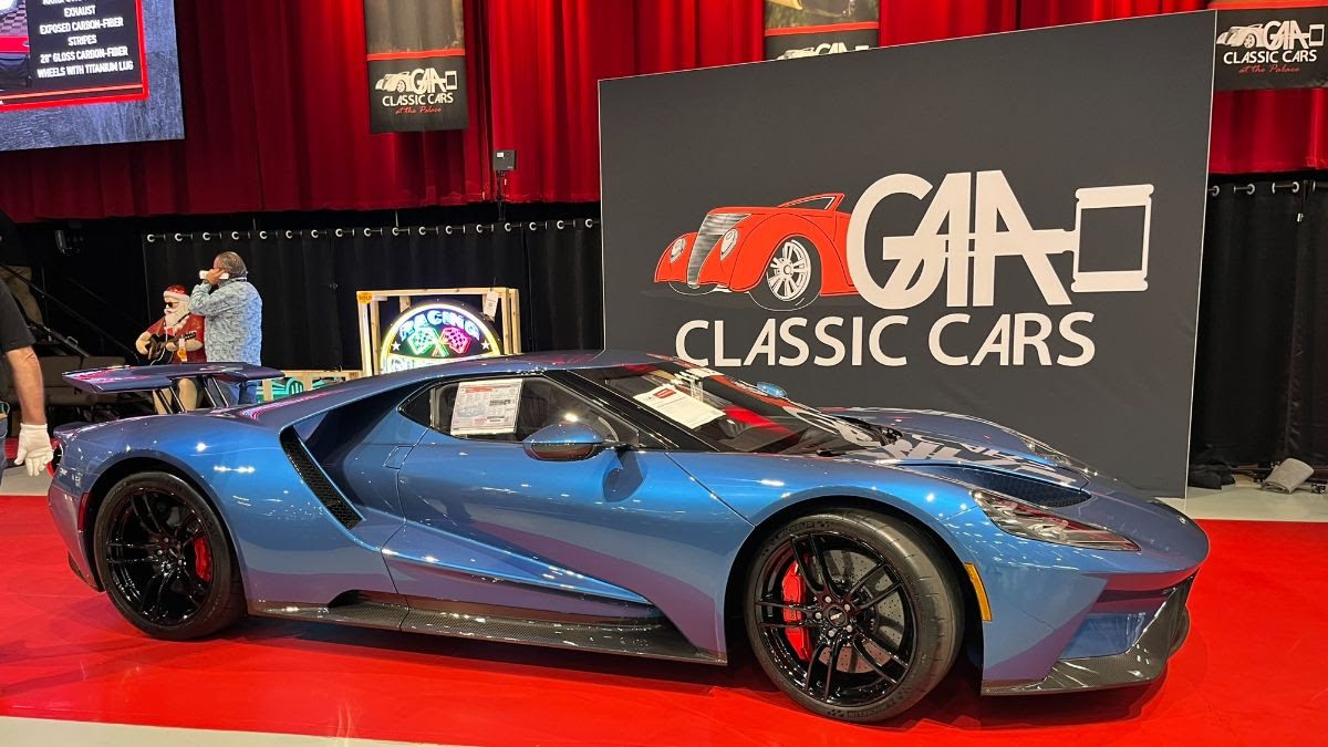 A blue Ford GT sports car is displayed indoors at a classic car show, parked in front of a sign that reads "GAA Classic Cars.