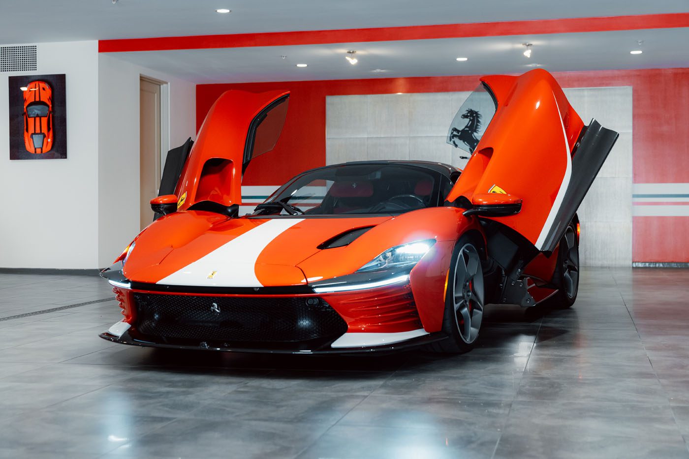 A Ferrari Daytona SP3, a true Modern Icon, with its scissor doors open is displayed in a modern showroom featuring gray tile floors and bold red and white wall accents.