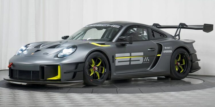 A matte gray Porsche GT2 RS Clubsport 25 race car with yellow accents, large rear wing, aerodynamic features, and the number 25 displayed on the side, is showcased in a studio setting, highlighting its race-ready design.